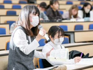 六法を片手に討論代表者に質問する一般参加の学生